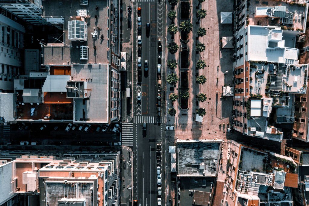 
A Aerial beautiful view of the cars driving on a road surrounded by buildings.